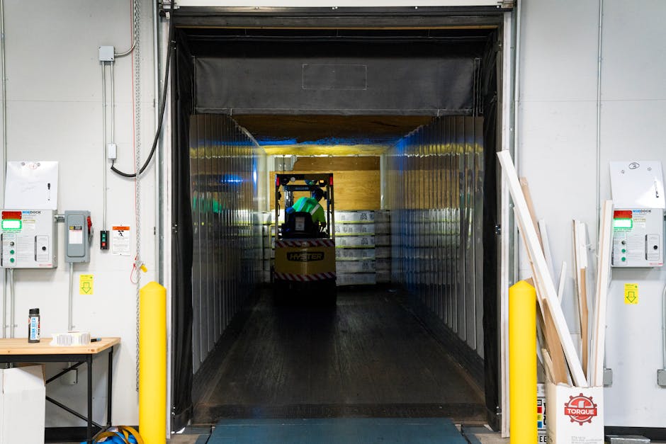 A forklift unloading goods at an industrial loading dock inside a warehouse.