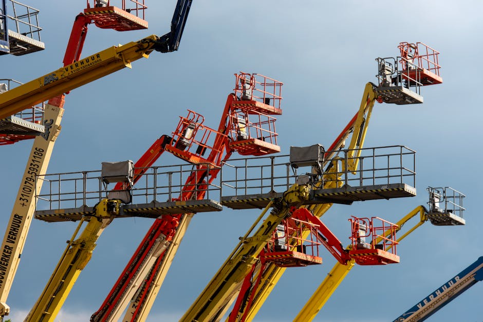 Vibrant boom lifts reaching skyward, showcasing industrial machinery against a clear blue backdrop.