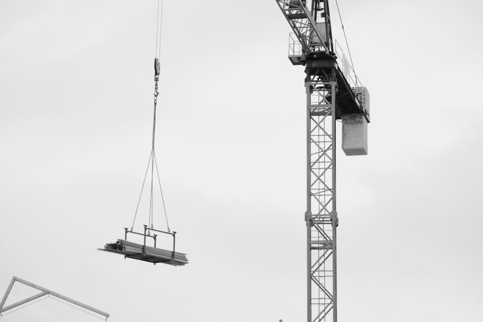 A black and white shot of a tower crane lifting materials at a construction site in Torrevieja.
