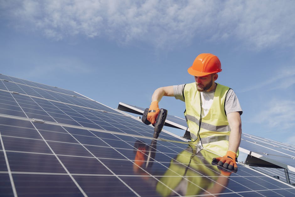 A solar technician wearing PPE installs photovoltaic panels for sustainable energy on a sunny day.