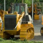 Multiple bulldozers parked in an outdoor construction area, ready for use.