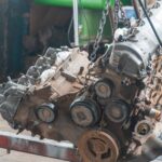 Close-up of a rusty engine lifted in a workshop for maintenance or repair.