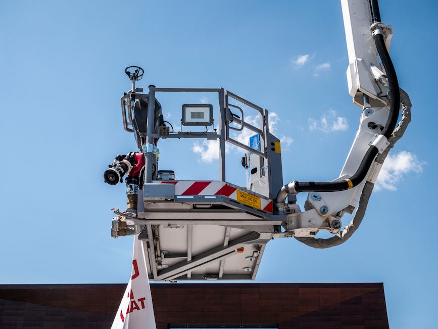 Firefighting ladder truck equipped with water cannon and hose against blue sky.