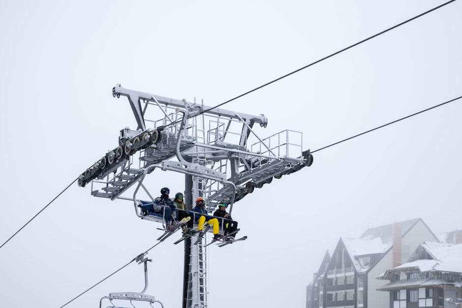 Group of skiers sitting on a ski lift at a snowy mountain resort. Overcast winter setting.