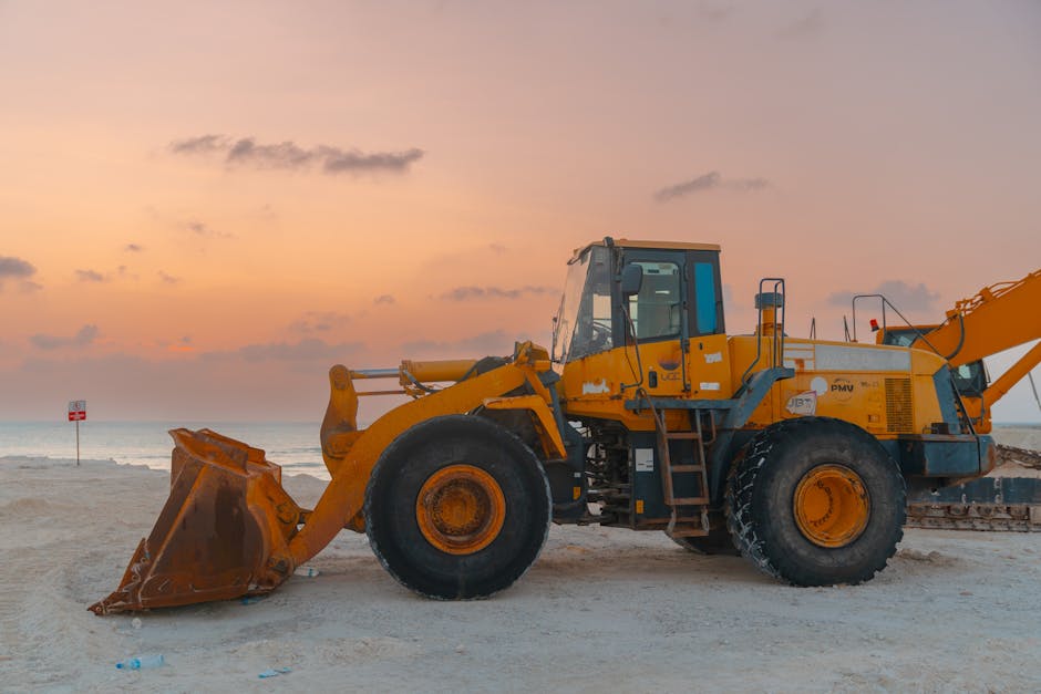 A bulldozer on a beach during sunset, ideal for projects involving coastal construction.