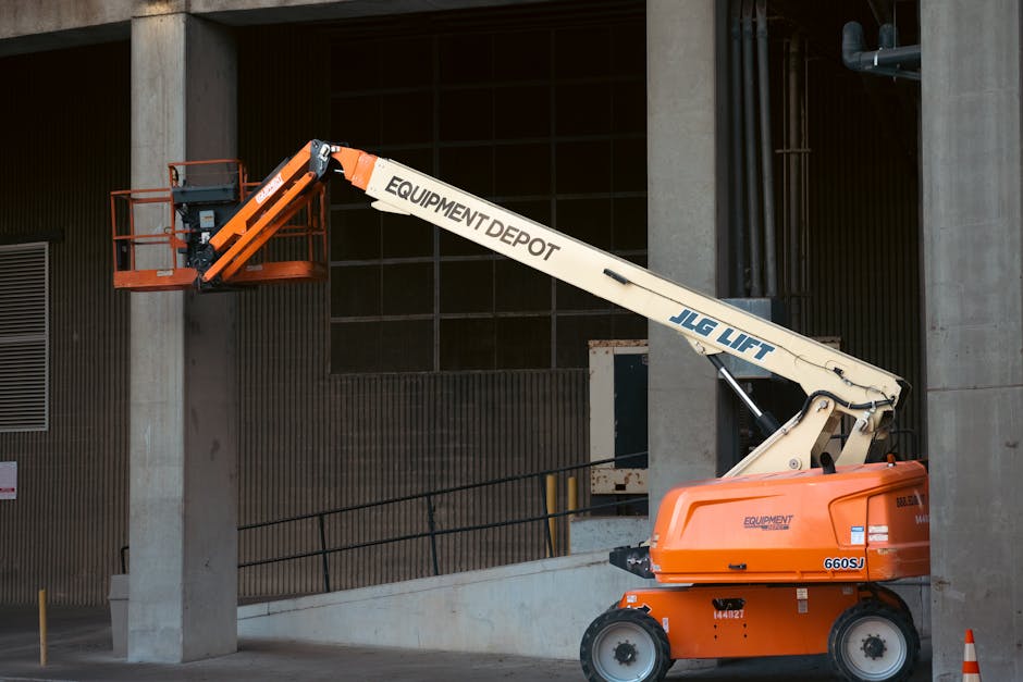 Orange JLG lift positioned at an industrial construction site, ready for use.