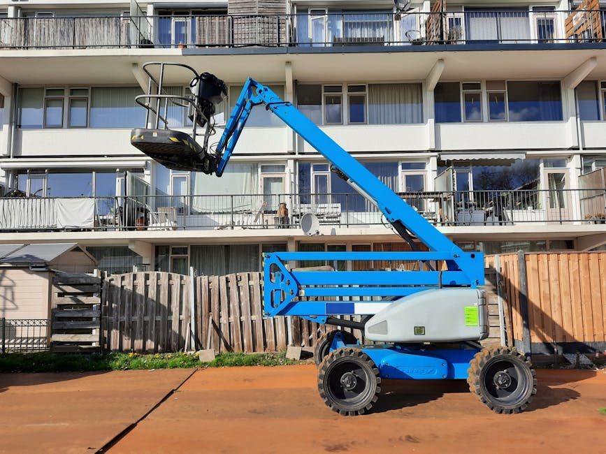 Blue construction lift in front of residential building under bright sunlight in Nederland.