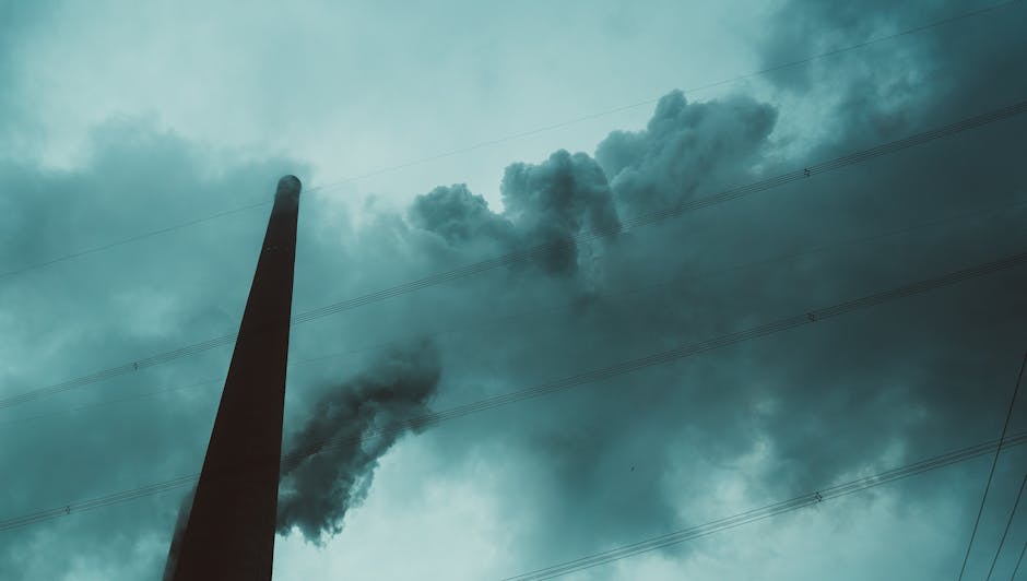 A chimney emitting smoke under a moody, cloud-filled sky, highlighting industrial atmosphere.