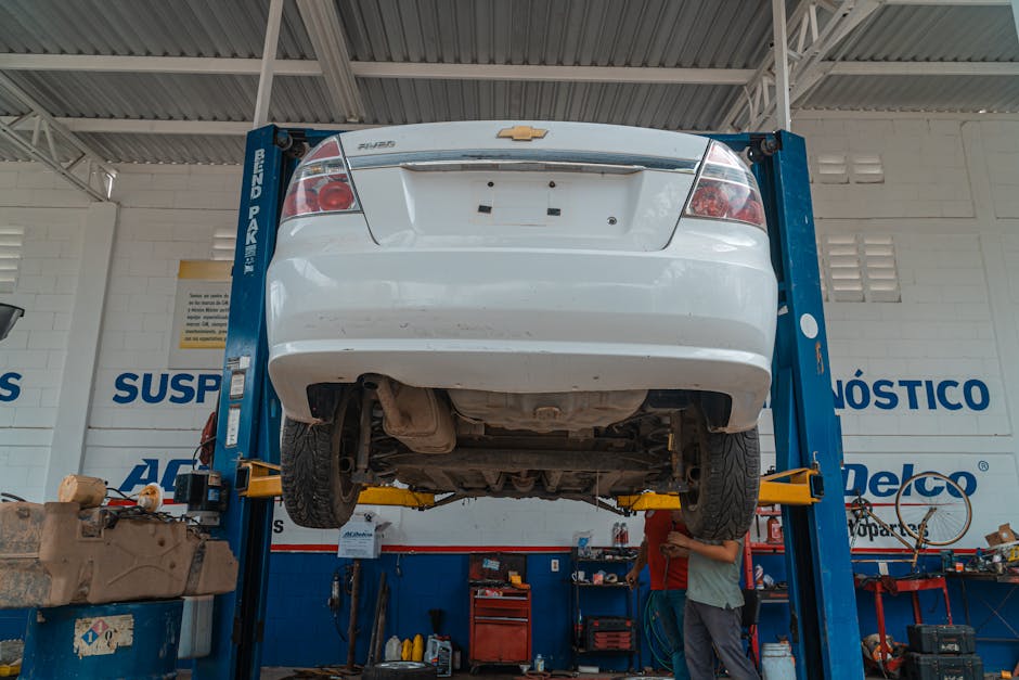 A white Chevrolet car is lifted for maintenance in an automotive repair shop.